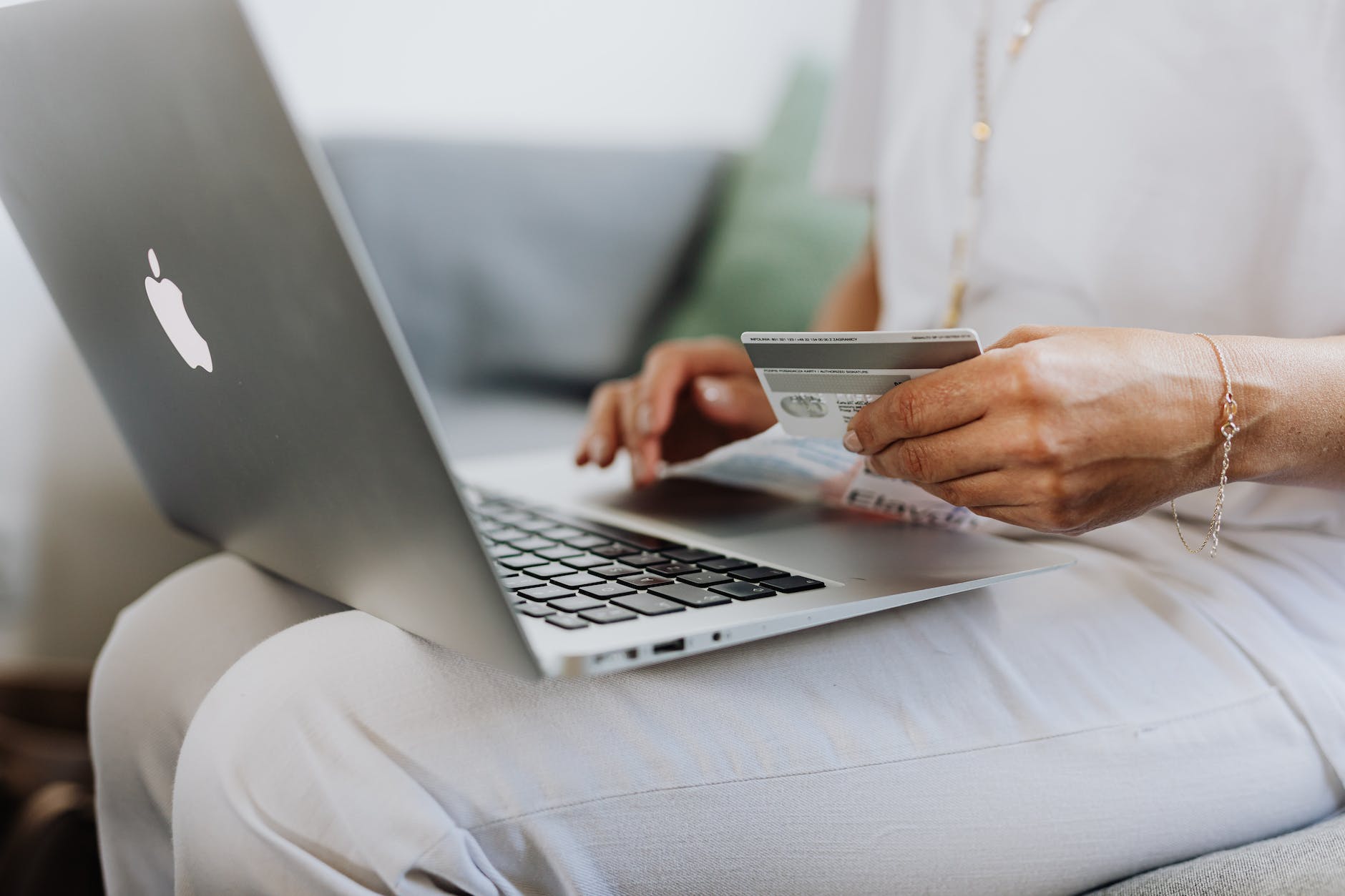 Person online shopping with laptop on their lap and holding a credit card